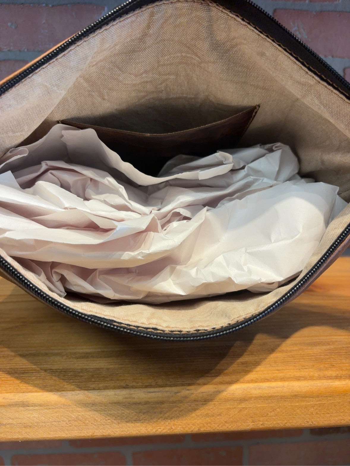 KC bag interior showing tan lining, one brown interior pocket and the zipper opening.