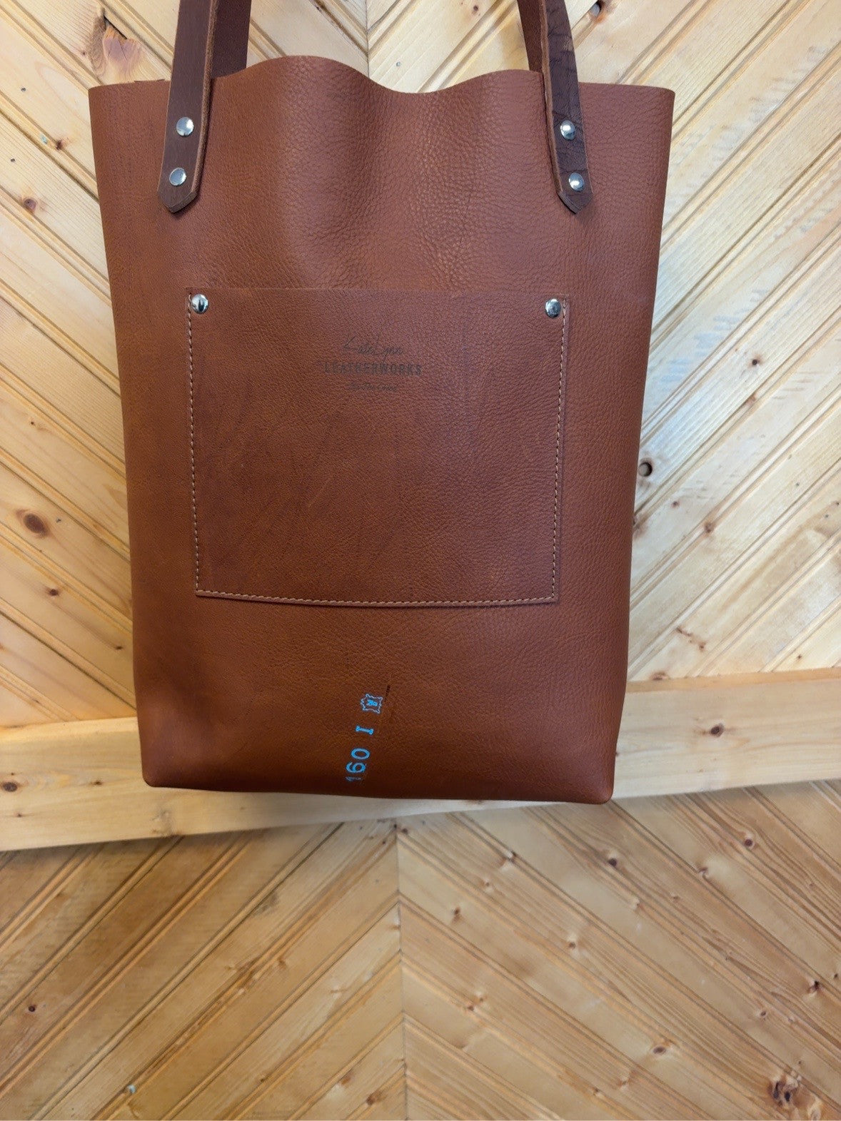 Back of the rich brown pebble-grain leather Bristow Bookbag showing an exterior patch pocket and silver-tone rivets.