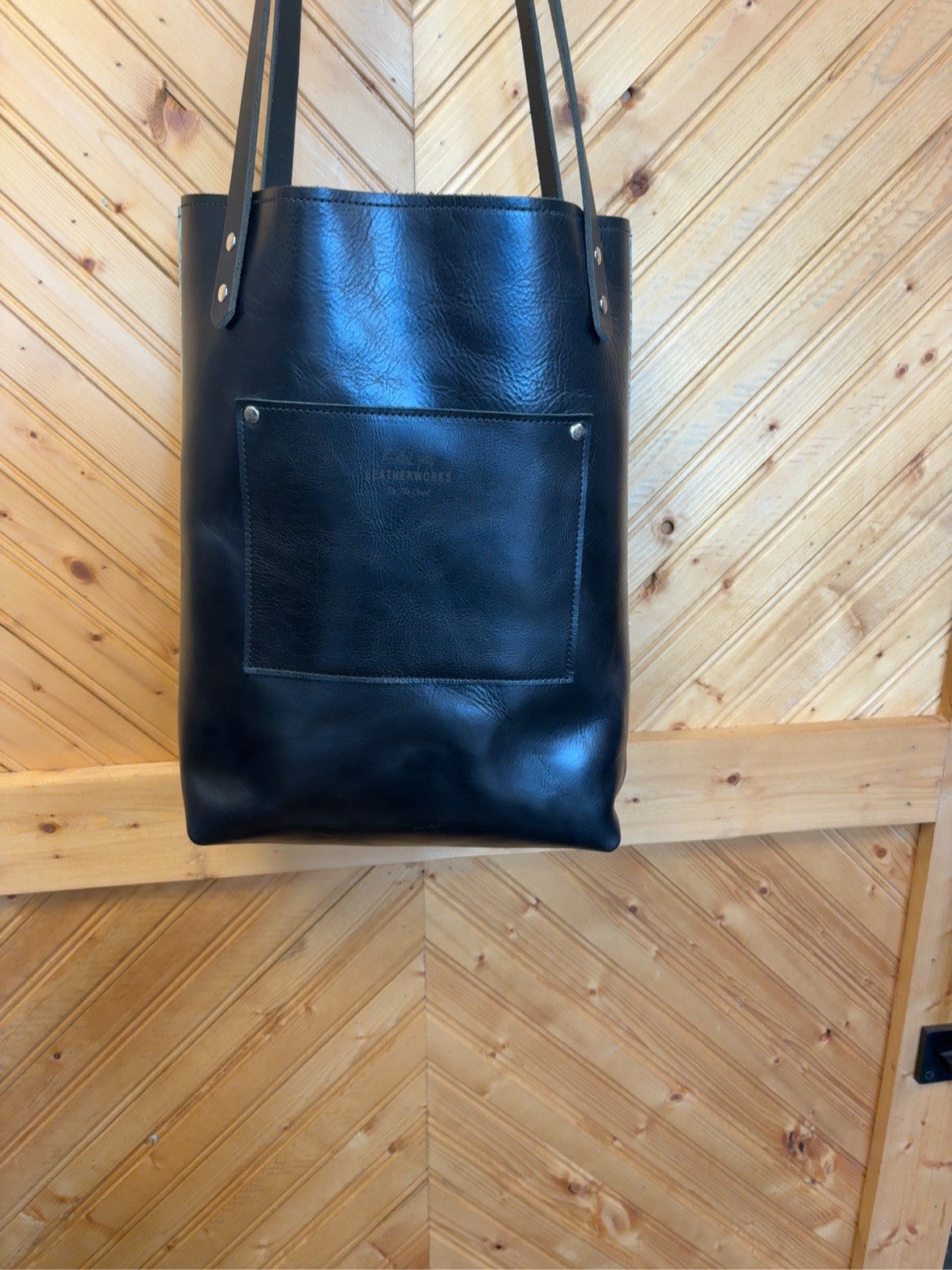 Black back of Bristow bookbag showing exterior patch pocket, black shoulder straps and silver-tone rivets.