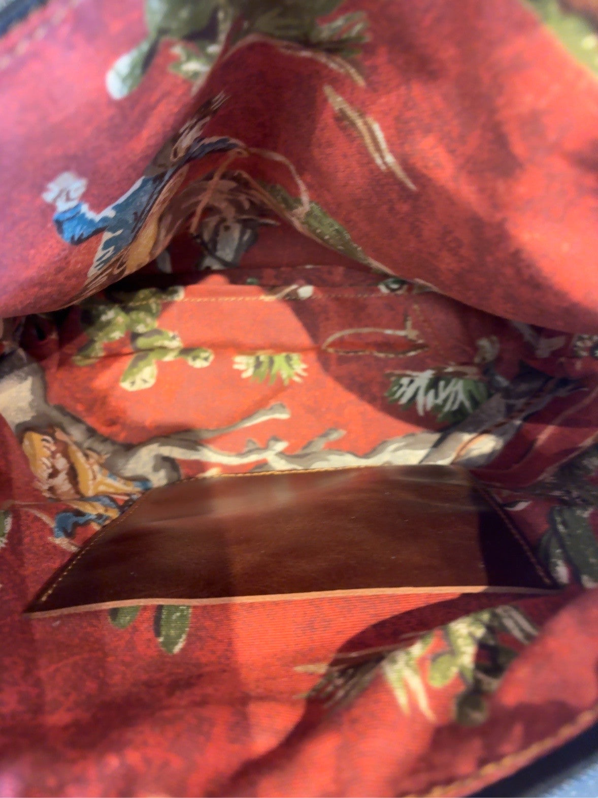 Red Western-print lining of KC bag showing one brown interior pocket.
