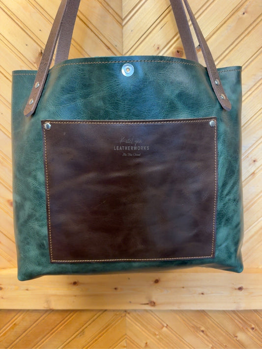 Reverse of deep-green Tucson Tote showing a large brown panel with the KateLynn Leatherworks logo and brown shoulder straps.