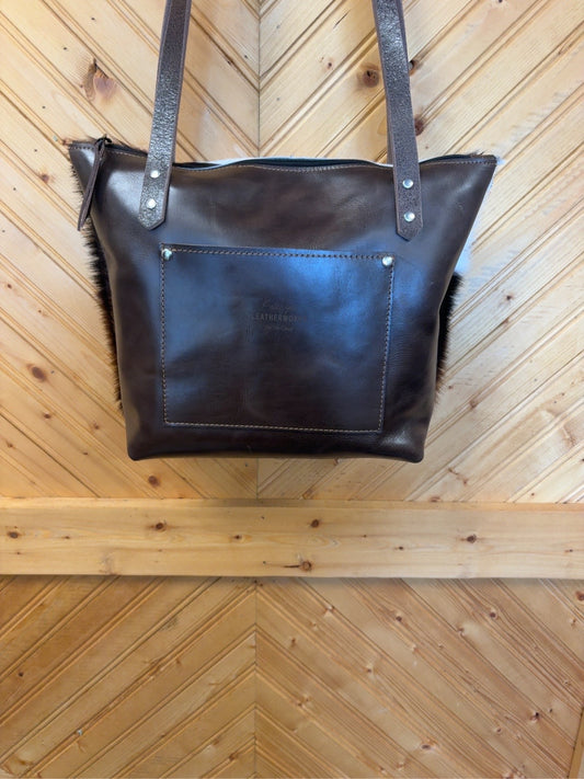 Brown leather back of Tucson Mini showing the exterior slip pocket, shoulder straps and zipper top