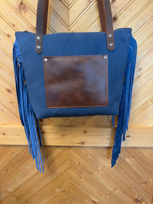 Blue back of Tucson Mini with a brown exterior slip pocket, brown shoulder straps and long blue fringe