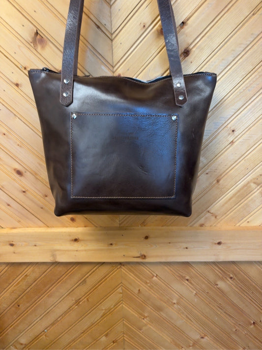 Dark brown back of Tucson Mini showing the exterior slip pocket, shoulder straps and zipper top