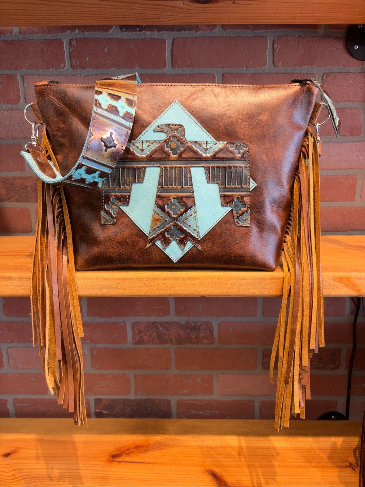 Brown KC bag with turquoise-backed Thunderbird design, matching patterned strap and long side fringe.