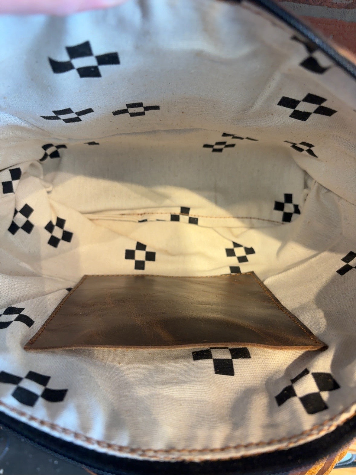 KC bag interior with cream-and-black geometric lining and one brown interior pocket.