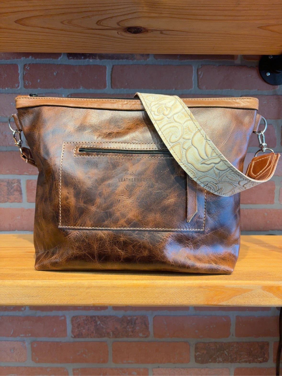 Brown leather back of the KC axis deer bag showing the exterior zipper pocket and Ivory Roses floral-patterned strap.