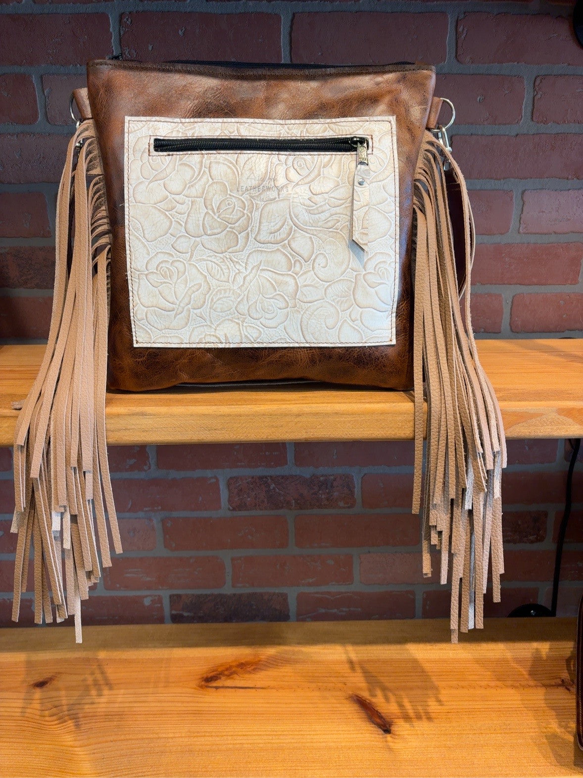 Back of the brown El Paso bag with an Ivory Roses embossed zipper pocket and tan side fringe