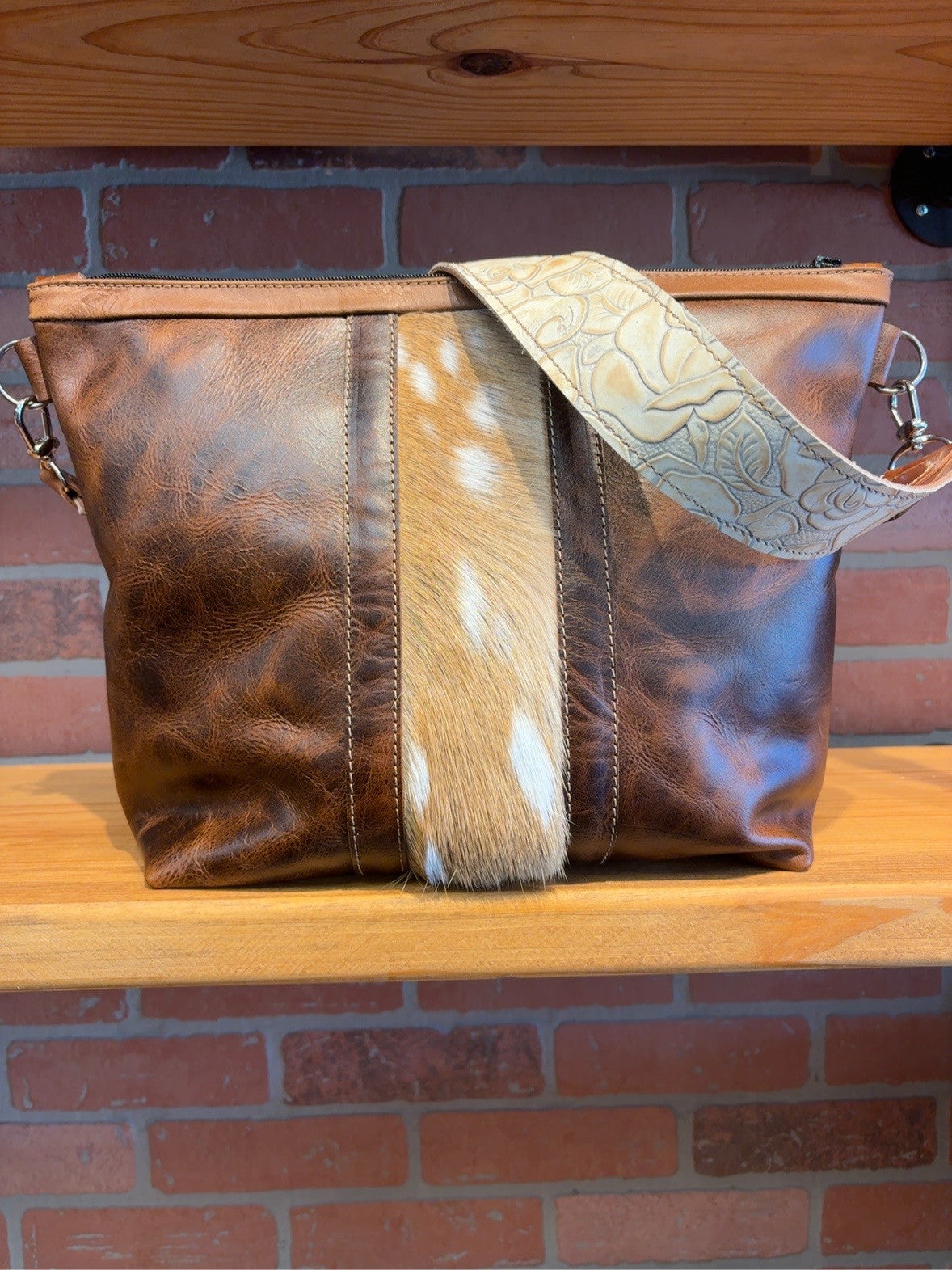 Brown KC bag with a spotted axis deer hide stripe down the center and an Ivory Roses floral-patterned shoulder strap.