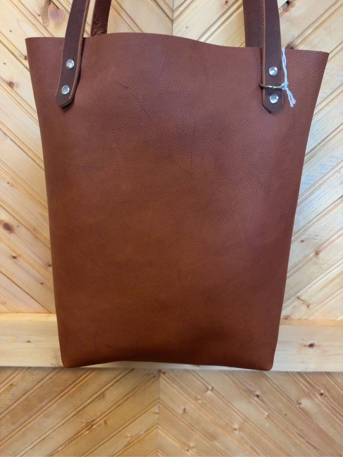 Front of the rich brown oil-tanned pebble-grain leather Bristow Bookbag with dark brown shoulder straps.