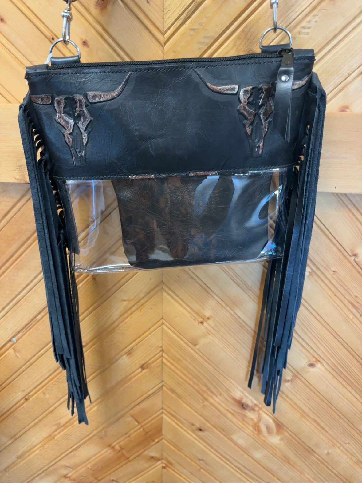 Black Arena crossbody bag with brown-accented longhorn skull detailing, clear lower body, long black fringe, zipper top and pouch