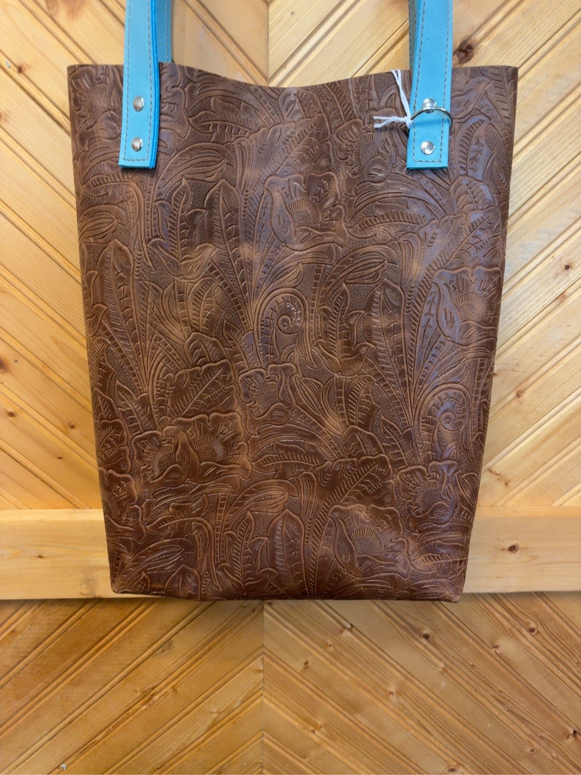Front of the Brown Floral & Turquoise Bristow Bookbag showing a brown floral pattern, turquoise shoulder straps and silver-tone rivets.