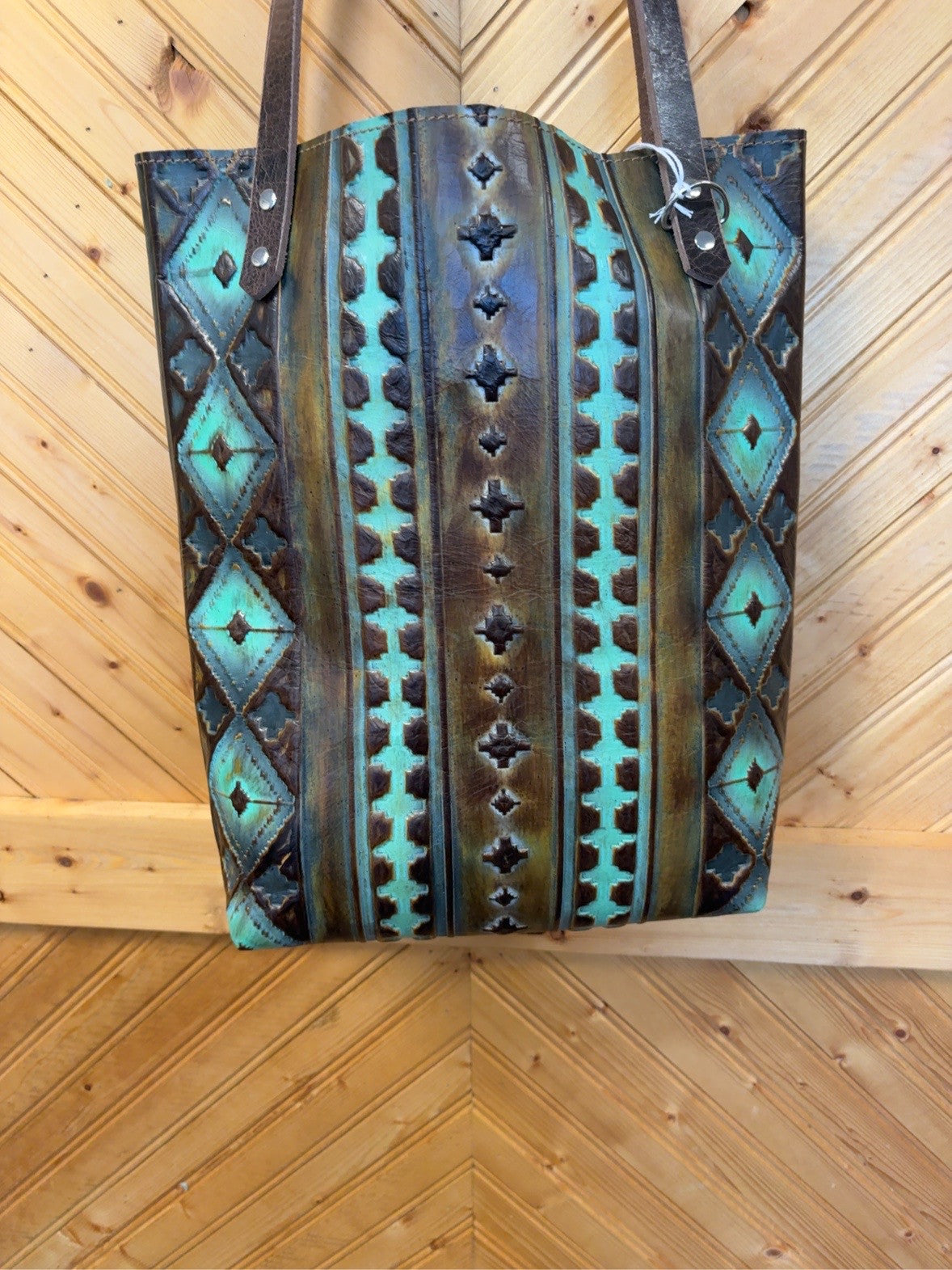 Front of Bristow Bookbag with turquoise and brown embossed geometric pattern, brown shoulder straps and silver-tone rivets