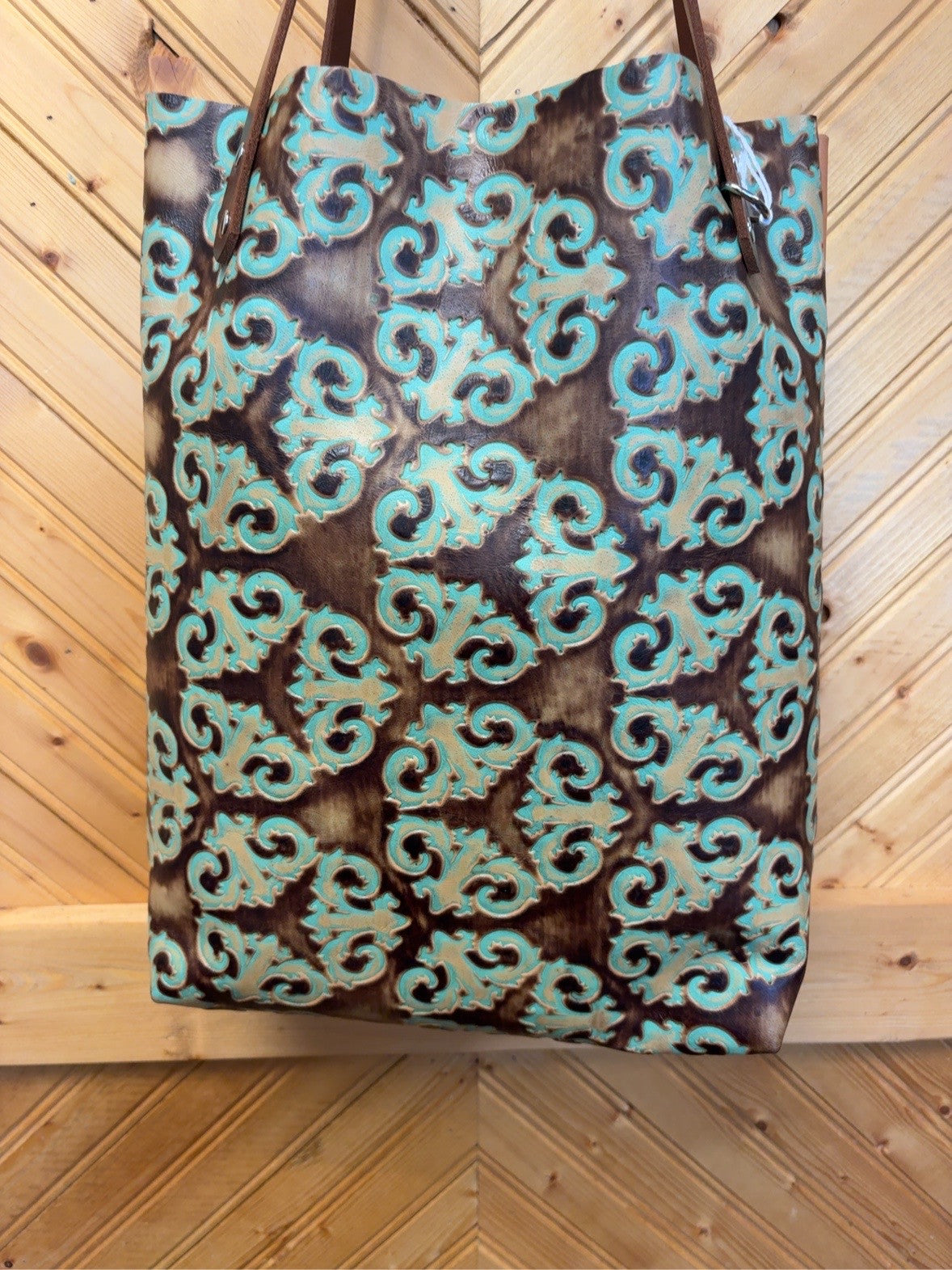 Front of the Bristow Bookbag with a turquoise and brown scroll pattern, brown shoulder straps and silver-tone hardware.