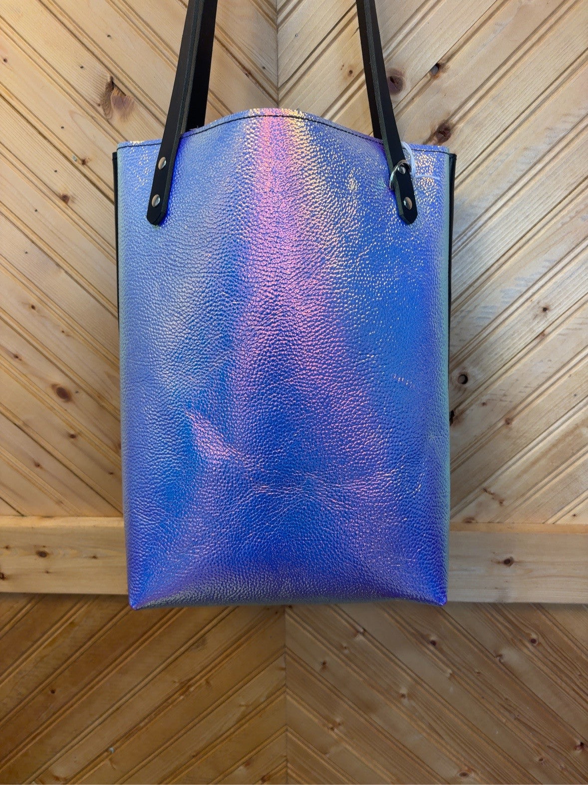 Front of the Unicorn Foil Bristow Bookbag with an iridescent blue-purple finish, pink-gold highlights, black shoulder straps and silver-tone rivets.