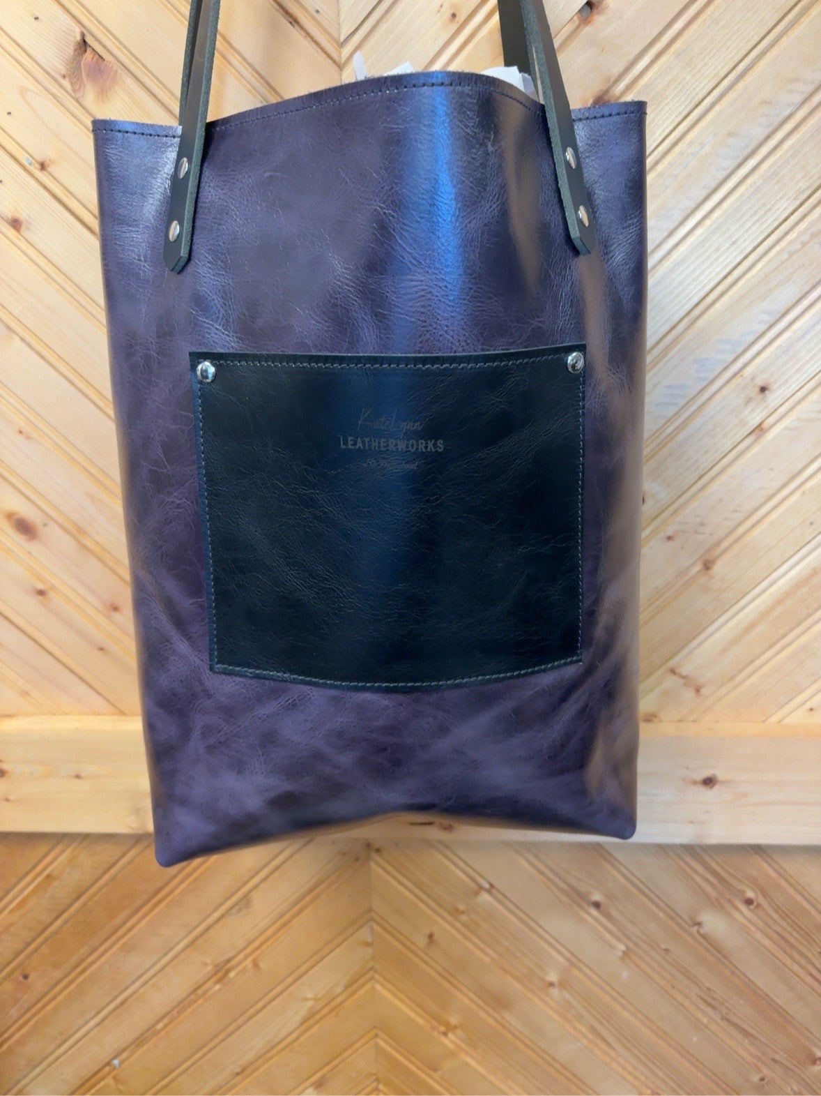 Plum back of the Unicorn Foil Bristow Bookbag with a black exterior pocket, KateLynn Leatherworks stamp, black shoulder straps and silver-tone rivets.