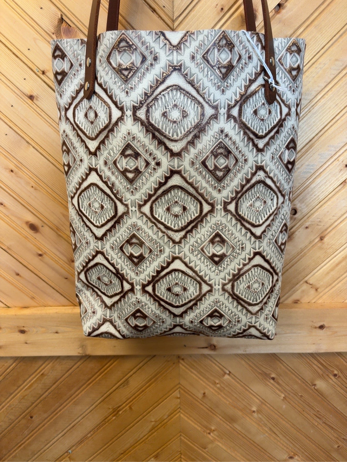 Front of cream, light gray and brown geometric Bristow bookbag with brown shoulder straps and silver-tone rivets.