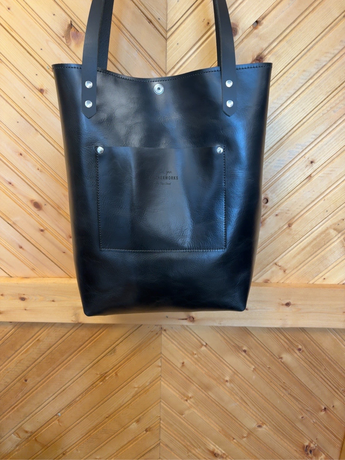 Black back of Bristow bookbag showing exterior patch pocket, black shoulder straps and silver-tone rivets.