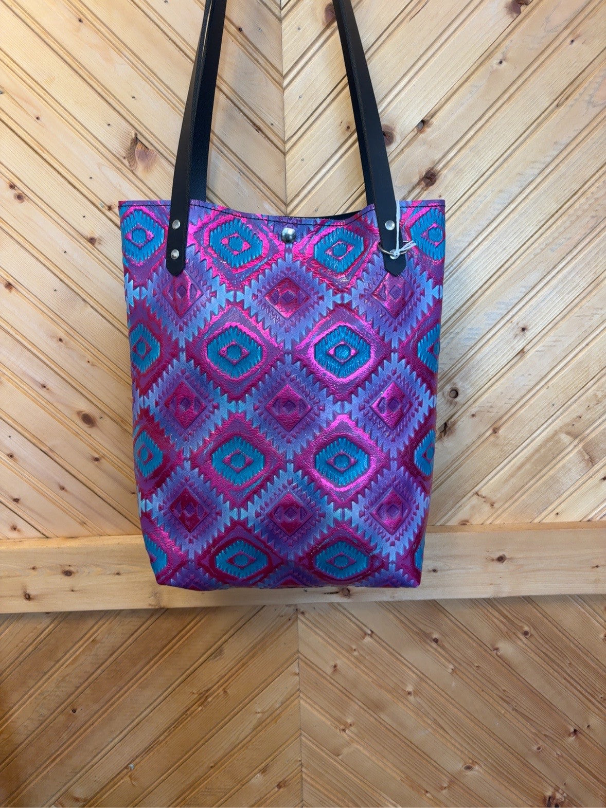 Front of Bristow bookbag with pink, turquoise and purple geometric pattern and black shoulder straps.
