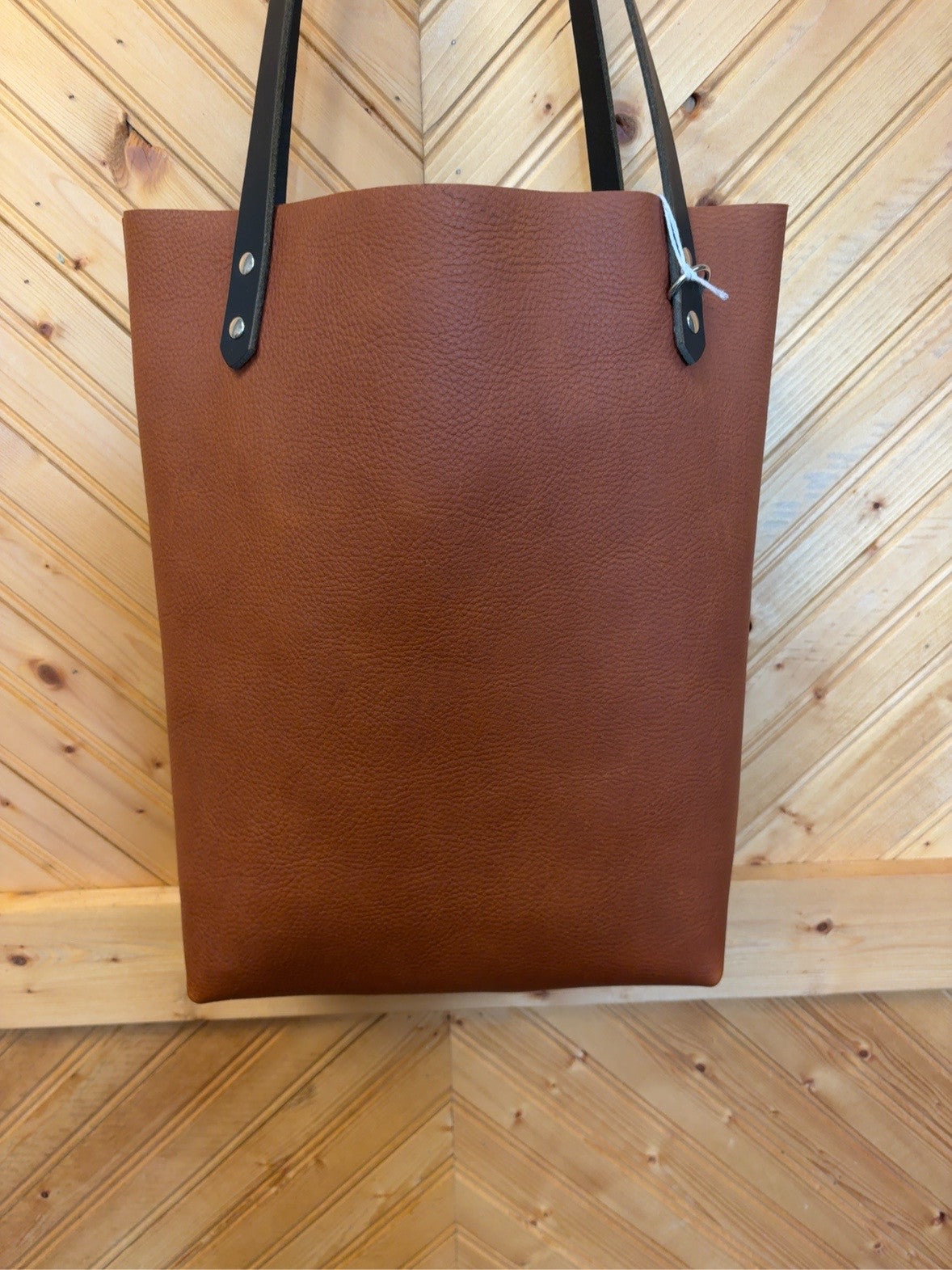 Front of rich brown pebble-grain Bristow bookbag with dark shoulder straps and silver-tone rivets.