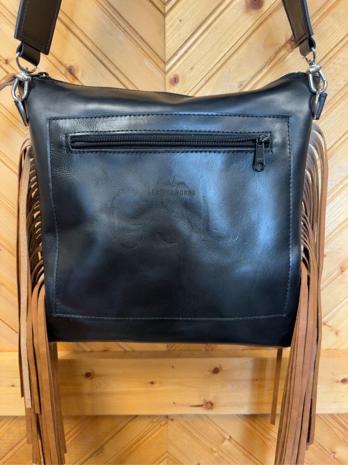 Black back of the El Paso goat hide bag showing the exterior zipper pocket and tan side fringe.