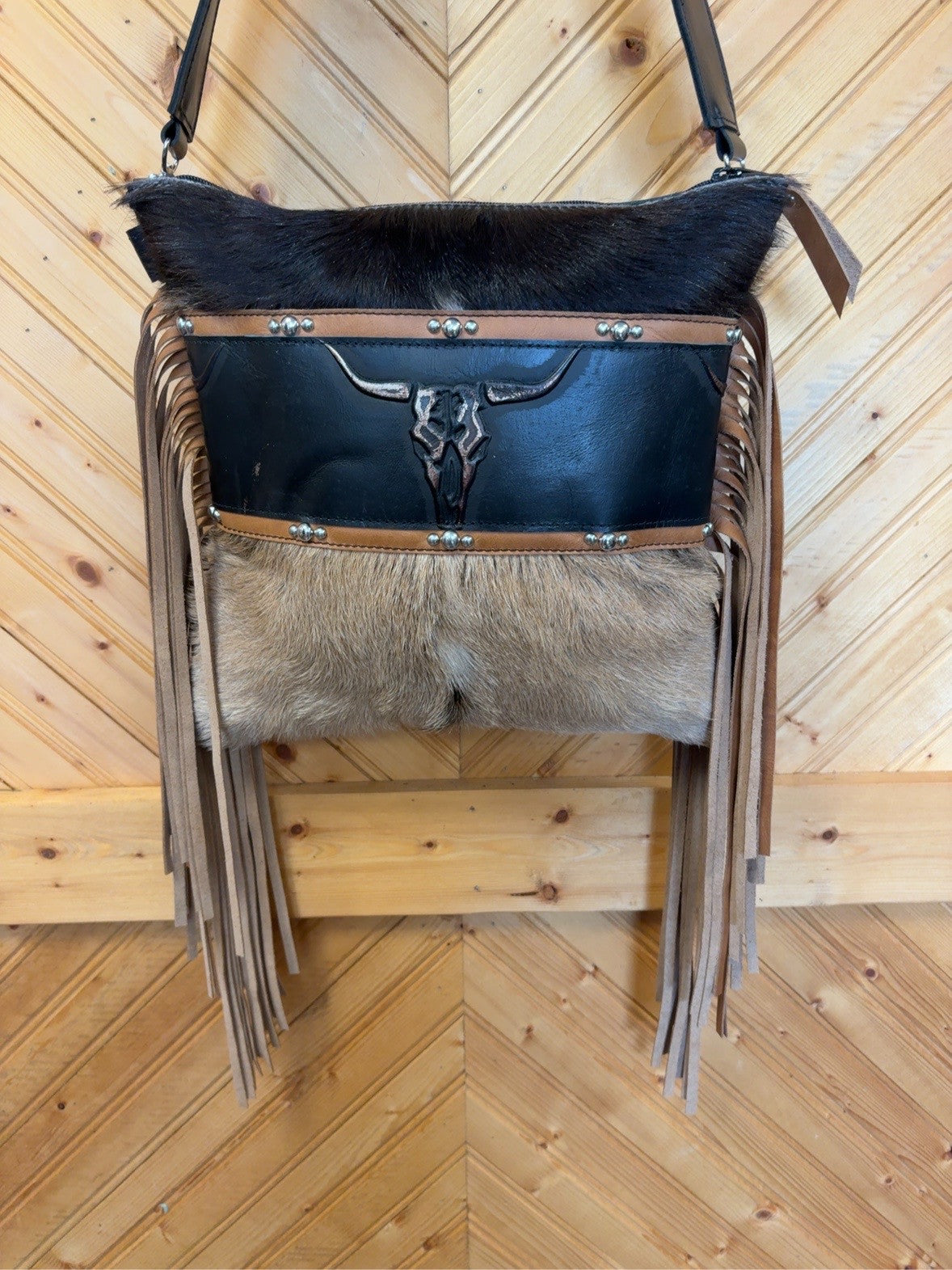 Front of the black-and-tan goat hide El Paso bag with a longhorn-skull detail, silver-tone studs and long tan fringe.