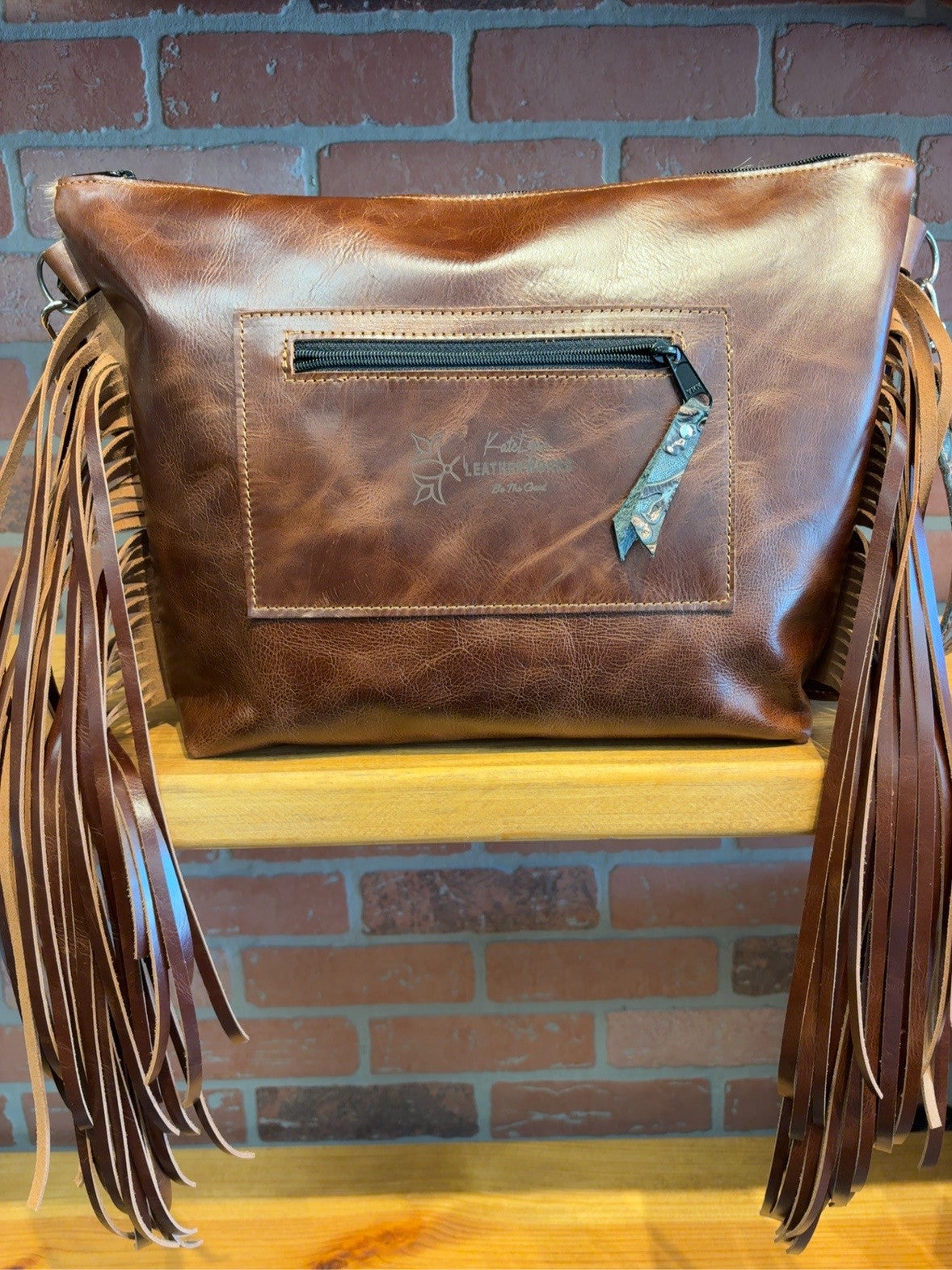 Brown back of KC bag with rear zipper pocket and long side fringe.