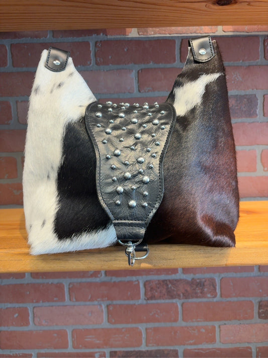 Front of black and white Lex shoulder bag showing its studded black flap and silver-tone clip closure.