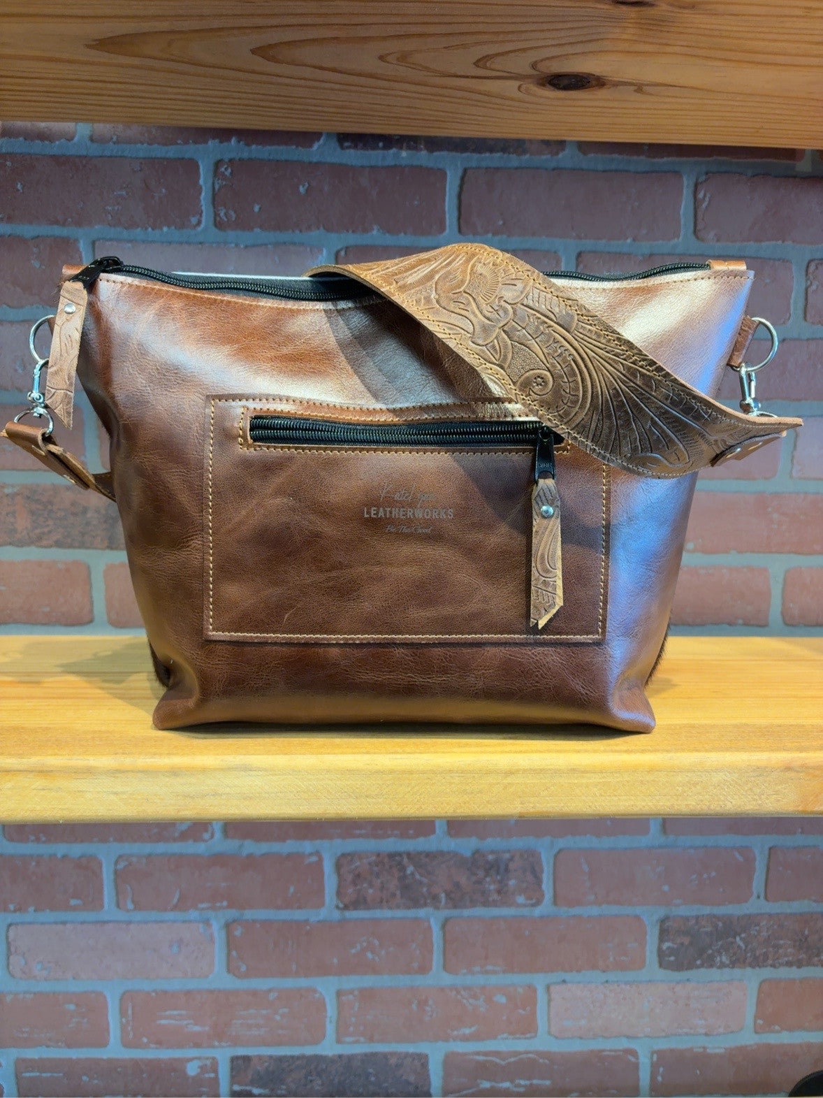 Brown back of the KC bag with an exterior zipper pocket and Honey Floral embossed strap.