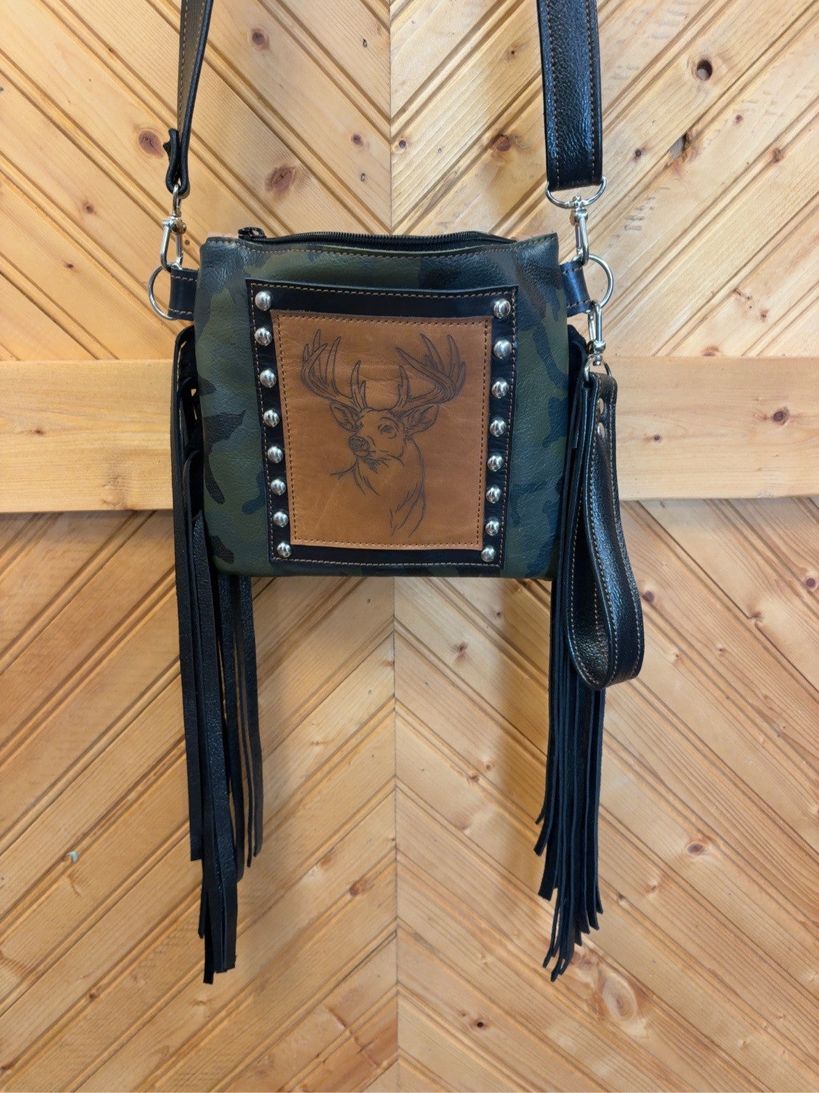 Front of camo leather Purse Sidekick with deer-head engraving, silver-tone studs, black fringe and wristlet strap