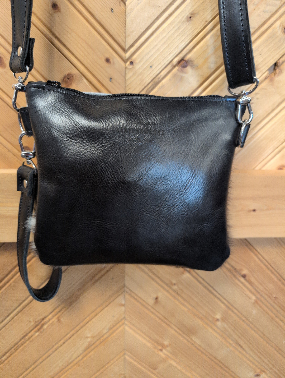 Black back of Purse Sidekick showing zipper-top closure, black crossbody strap and wristlet strap