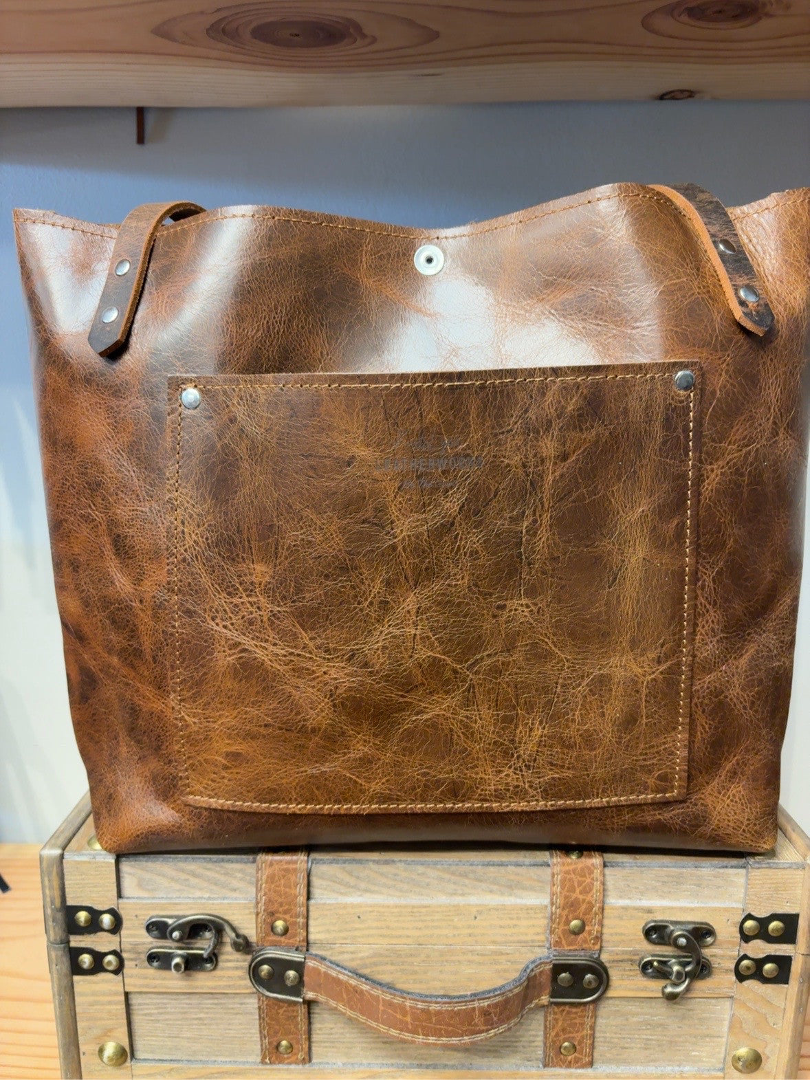 Back view of brown Tucson Tote showing the rectangular exterior pocket and handles.