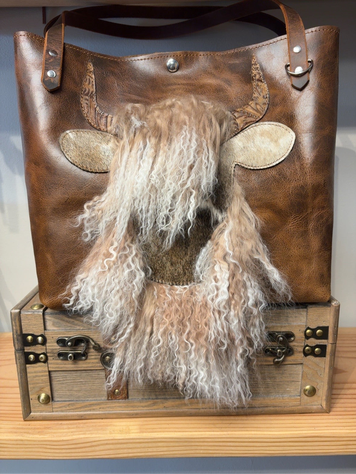 Front of brown Tucson Tote with cowhide cow-face design and long, curly Tibetan lamb hair.