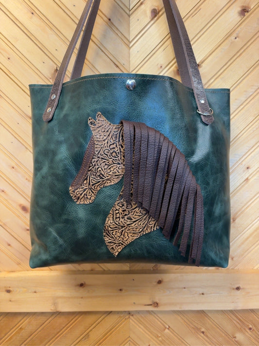 Front of deep-green Tucson Tote with a patterned horse design, brown fringe mane and brown shoulder straps.