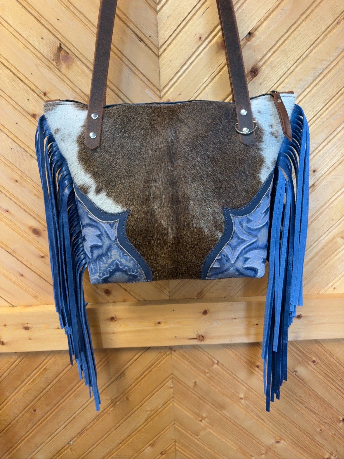 Front of Tucson Mini with brown-and-white cowhide, Blue Laredo corner accents, long blue side fringe and brown shoulder straps