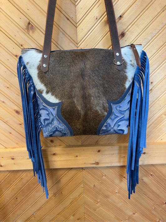 Front of Tucson Mini with brown-and-white cowhide, Blue Laredo corner accents, long blue side fringe and brown shoulder straps