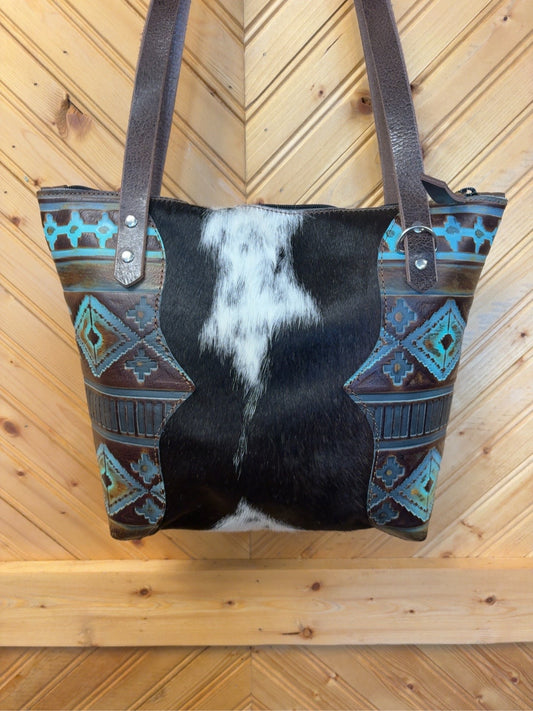 Front of Tucson Mini with a black-and-white cowhide center, Chocolate Navajo embossed side panels and dark brown shoulder straps
