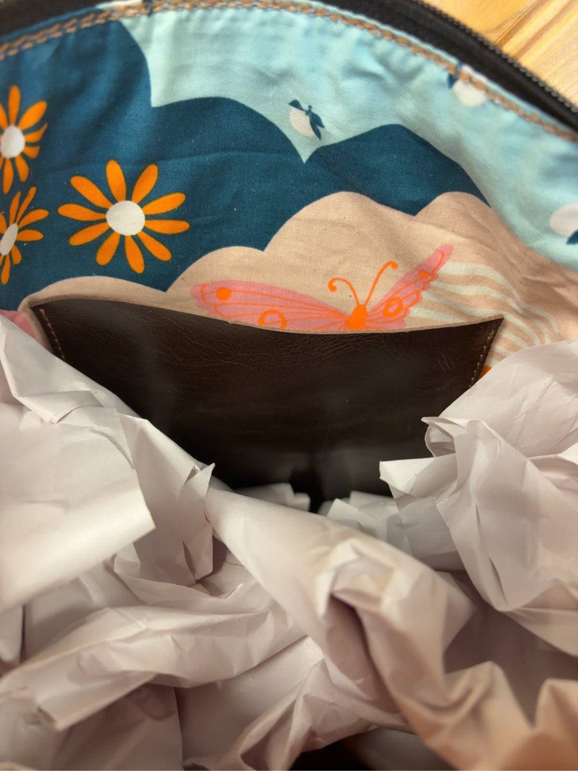 Tucson Mini interior with colorful floral-and-butterfly lining, a dark brown slip pocket and zipper top