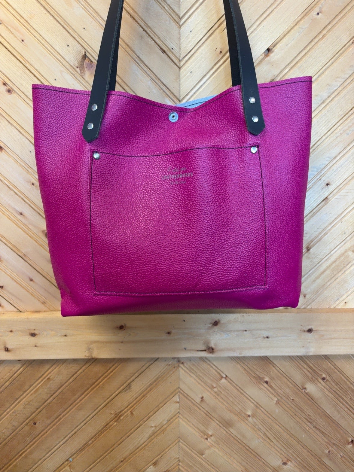 Magenta back of the Tucson tote showing the exterior slip pocket and black shoulder straps.