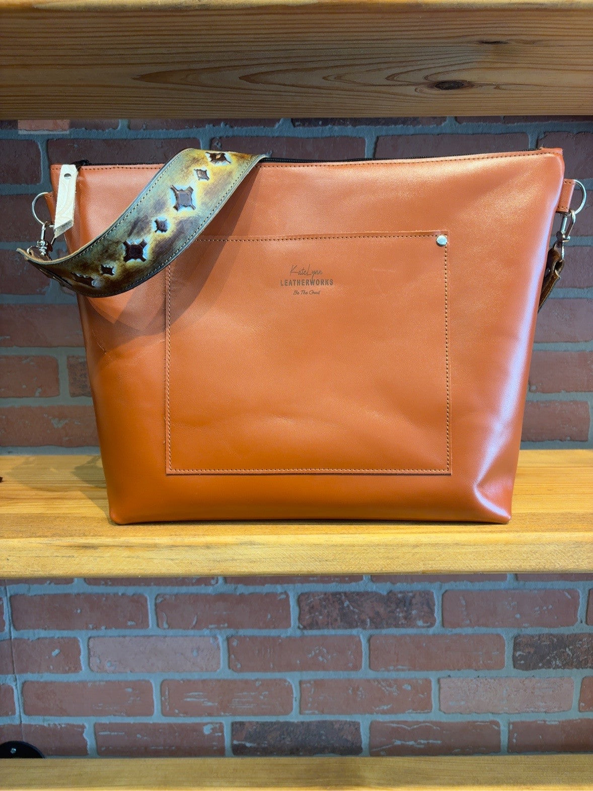 Back of the Tucson tote showing the exterior slip pocket, zipper top and wide patterned shoulder strap.