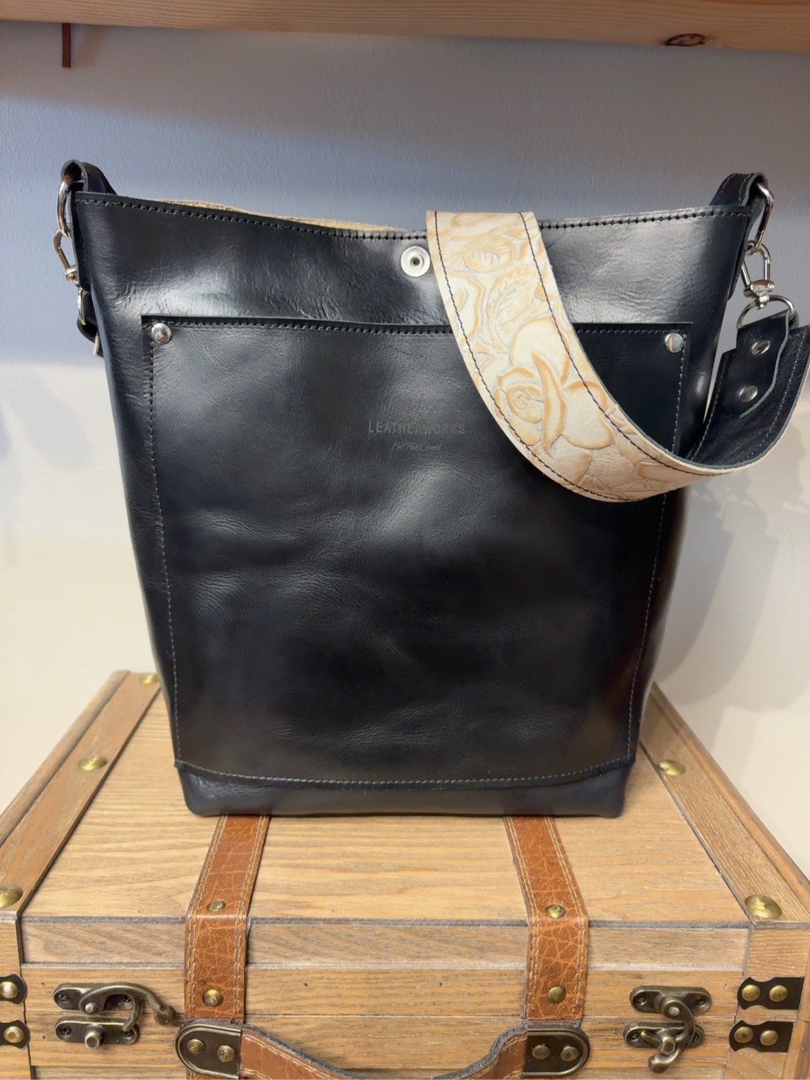 Black leather back of the Yukon bag with exterior pocket and ivory rose-embossed shoulder strap